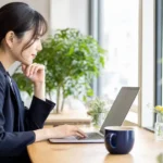 ノートパソコンを見ながら転職活動について調べる女性