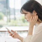 スマートフォンを見ながら転職活動について悩む女性