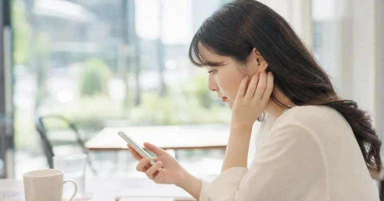 スマートフォンを見ながら転職活動について悩む女性