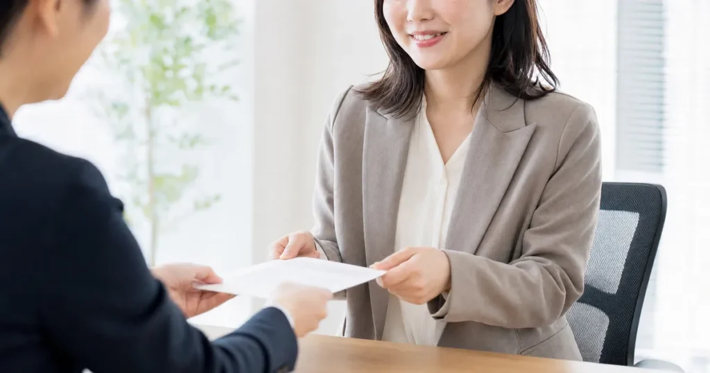 転職エージェントとの面談で書類を受け取る女性