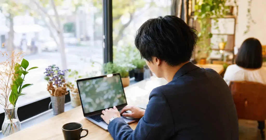 カフェでノートPCを使って作業するエンジニア