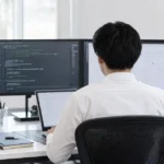QAエンジニアがコードを確認しながらテスト作業を行う後ろ姿